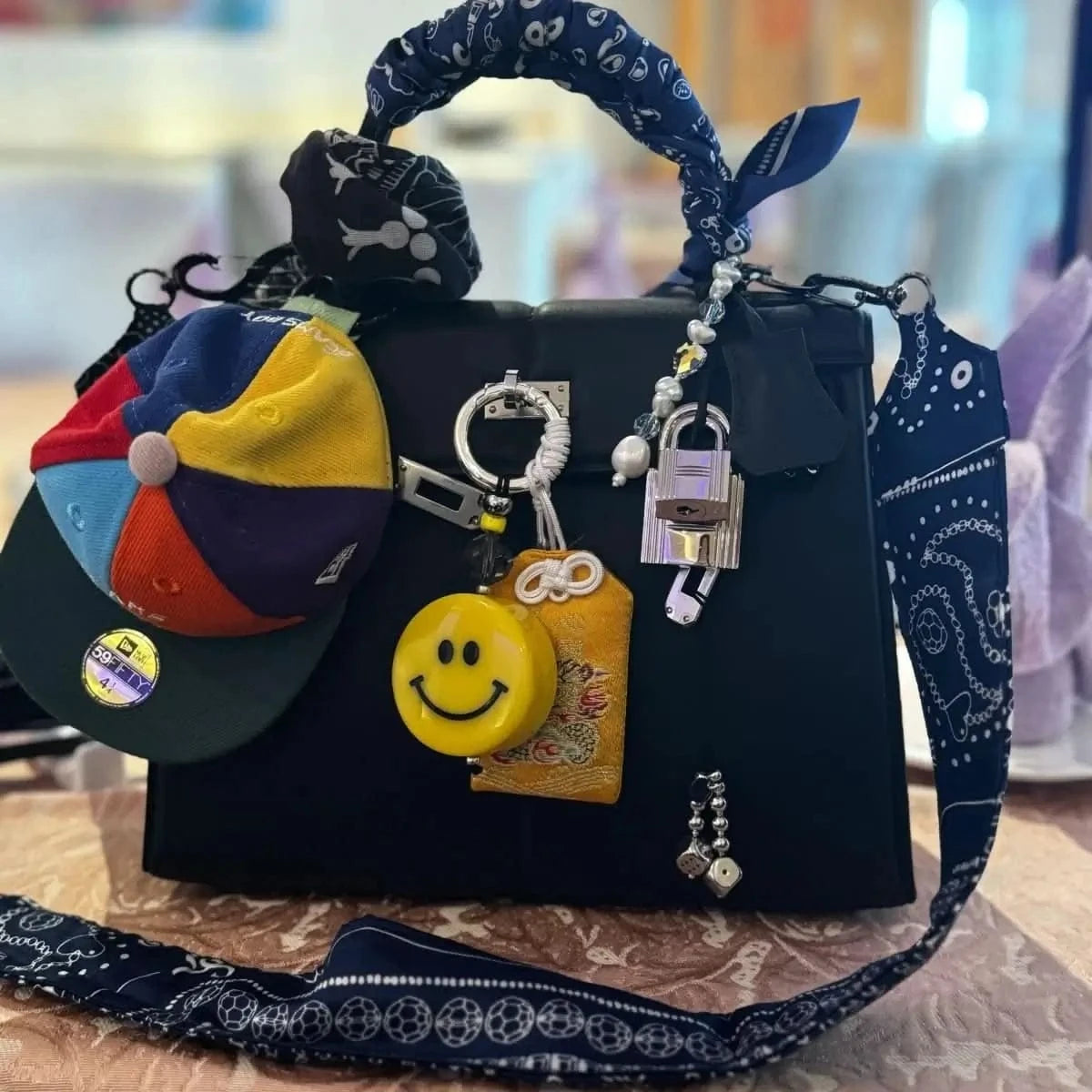 Bead Parade silk twilly scarf tied in a bow on a luxury Birkin bag, showcasing its intricate bead-inspired pattern.