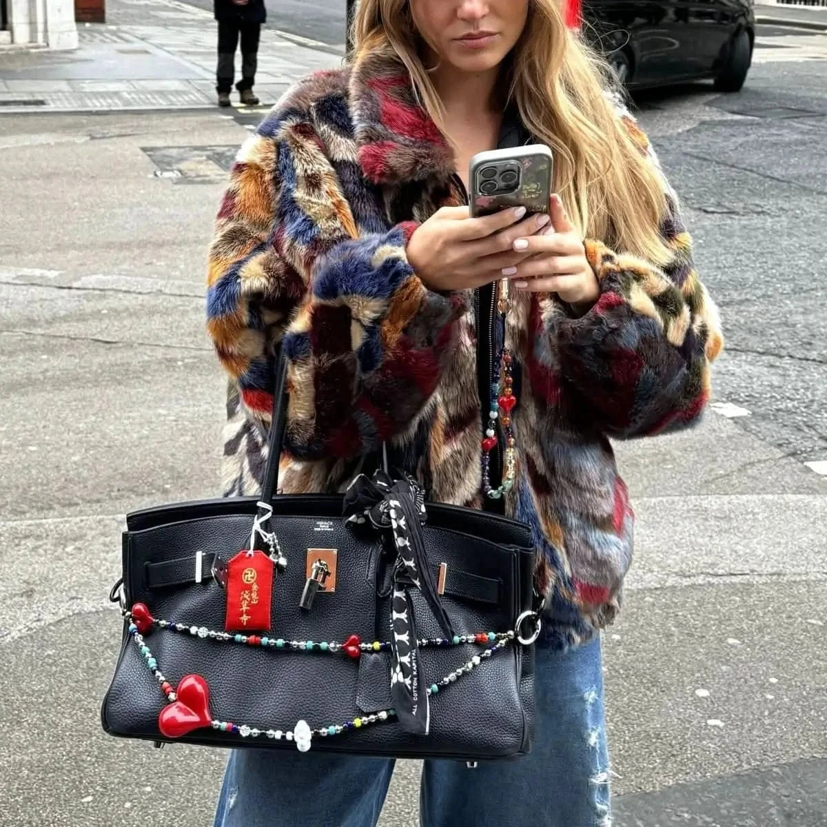 Big Love² Bag Charm draped over the handle of a classic Birkin bag, showcasing its chic design and the contrast between the vibrant beads and the bag's texture.