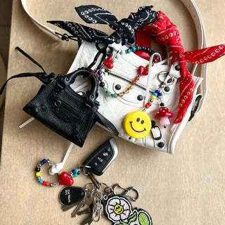 The Bead Parade Bandana folded diagonally, emphasizing its versatility as a fashion accessory, with the bold red color and unique pattern adding a pop of style.