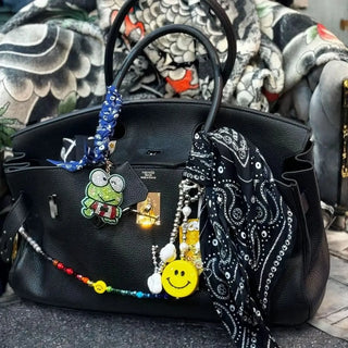Close-up of the black Bead Parade bandana wrapped around a luxury bag’s strap, showcasing its versatile and fashionable use as an accessory.