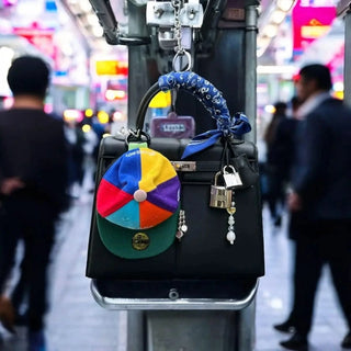 Bead Parade silk twilly scarf in indigo, elegantly wrapped around the handle of a designer handbag, adding a vibrant accent.
